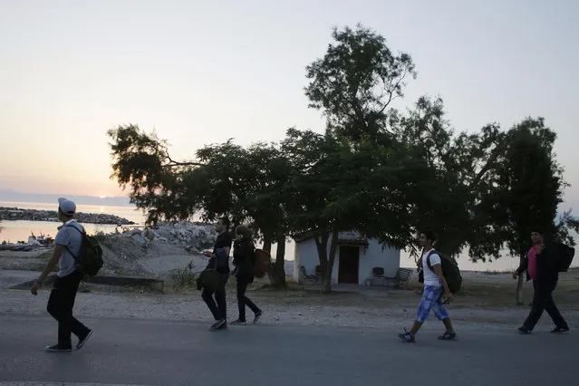 Syrian migrants walk next to a small Greek Orthodox church as the sun rises after their arrival from Turkish coasts at a beach in Mytilene, on the northeastern Greek island of Lesvos, early Tuesday, June 16, 2015. Lesvos has been bearing the brunt of a huge influx of migrants from the Middle East, Asia and Africa crossing from the Turkish coast to nearby Greek islands. More than 50,000 migrants have arrived in Greece already this year, compared to 6,500 in the first five months of last year. (AP Photo/Thanassis Stavrakis)