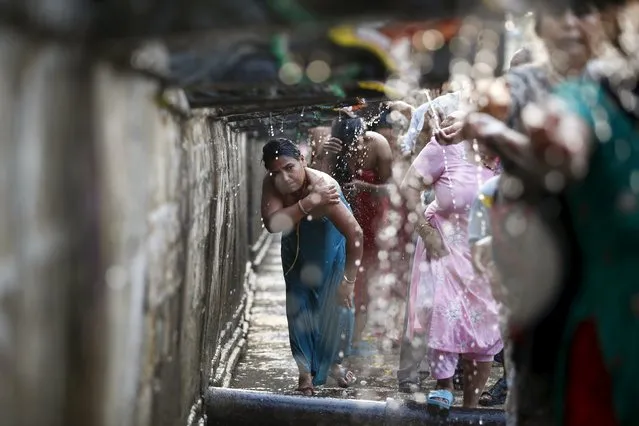 A devotee (C) takes a holy bath at the Balaju Baise Dhara (22 water spouts) during the Baishak Asnan festival in Kathmandu, Nepal, April 22, 2016. (Photo by Navesh Chitrakar/Reuters)