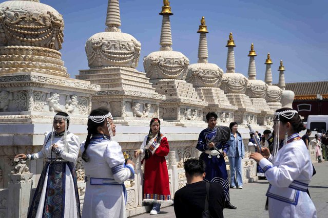 Tourists wearing ethnic minority costumes pose for souvenir photos taken at Dazhao Temple, a Tibetan Buddhist monastery, during a five-day holiday for international labor day in Hohhot, north China's Inner Mongolia Autonomous Region, Thursday, May 2, 2024. (Photo by Andy Wong/AP Photo)