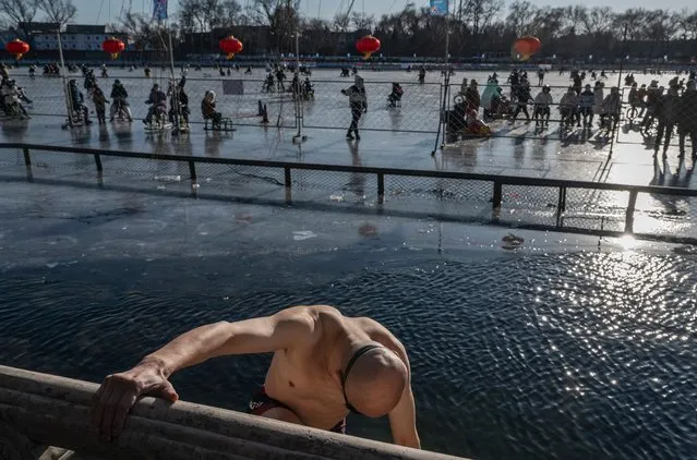 A man prepares to go for a swim in icey waters as others use an outdoor rink on Shichahai Lake at Houhai on January 15, 2022 in Beijing, China. (Photo by Kevin Frayer/Getty Images)