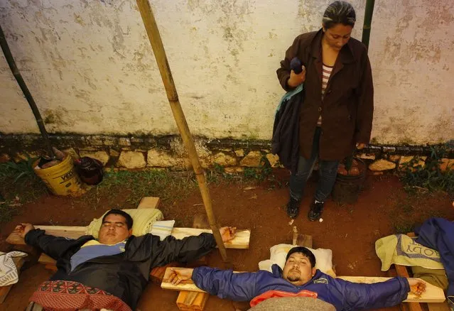 Men lay with their hands nailed to wooden crosses to protest the dismissal of 50 bus drivers, including themselves, outside the company's office in Luque, Paraguay, Wednesday, July 1, 2015. The bus drivers were fired from the bus line, La Limpe'a, one of many private bus companies that service the capital city of Asuncion. (Photo by Cesar Olmedo/AP Photo)
