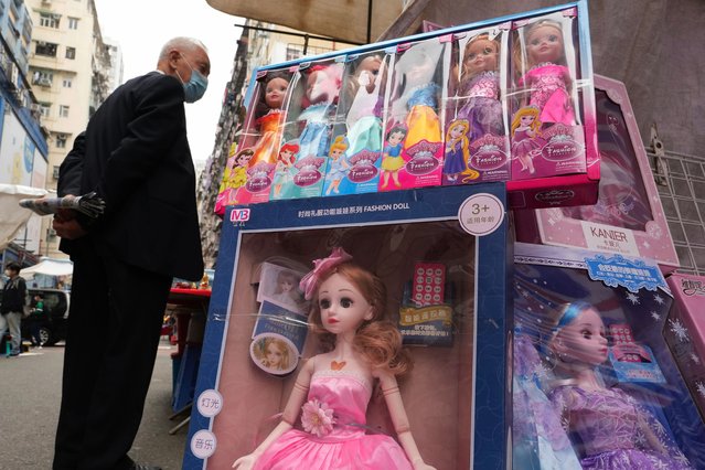 A man wears a face mask walks past a booth selling toys at an outdoor market in Hong Kong, Thursday, February 10, 2022. Hong Kong leader Carrie Lam announced on Tuesday that places of worship and hair salons must close from Thursday until at least Feb. 24, when a “vaccine pass” will be rolled out that permits only vaccinated people to visit venues such as shopping malls and supermarkets. (Photo by Vincent Yu/AP Photo)