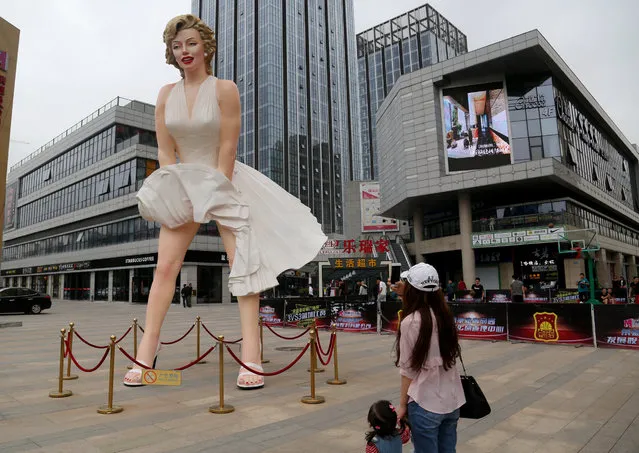 A woman take pictures with a mobile phone of a giant statue of Marilyn Monroe standing near a shopping mall in Changzhou, Jiangsu Province, China, May 7, 2016. (Photo by Reuters/Stringer)