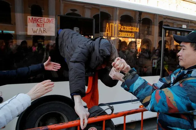 A protester is helped to escape a bus used to transport demonstrators to the police station, during an anti-war protest against the Russian invasion of Ukraine, after President Vladimir Putin authorised a massive military operation, in Saint Petersburg, Russia on February 27, 2022. (Photo by Anton Vaganov/Reuters)
