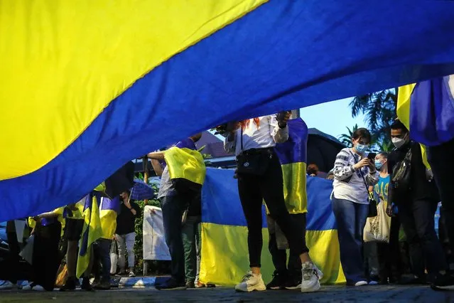 Protesters hold a giant Ukraine national flag near Independence Square during a protest over Russia's invasion of Ukraine, in Kuala Lumpur, Malaysia, 05 March 2022. Russian troops entered Ukraine on 24 February prompting the country's president to declare martial law and triggering a series of severe economic sanctions imposed by Western countries on Russia. (Photo by Fazry Ismail/EPA/EFE/Rex Features/Shutterstock)