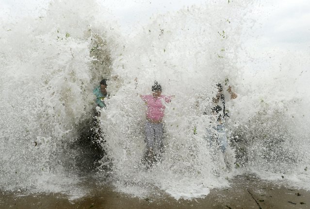Tourists standing near the sea shore are hit by a wave, which surged past a barrier under the influence of Typhoon Chan-hom, in Qingdao, Shandong province, China, July 12, 2015. (Photo by Reuters/Stringer)