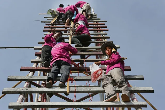 A rocket building team climbs the scaffolding and prepares to launch their rocket at the Bun Bang Fai festival on May 11, 2014 in Yasothon, Thailand. During the Bun Bang Fai rocket festival, Thai residents launch enormous home-made rockets into the air to gain Buddhist merit and to celebrate the beginning of the rainy season. (Photo by Taylor Weidman/Getty Images)