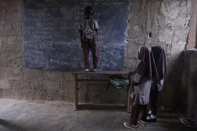 Students work out math problems on a blackboard inside a classroom lit by sunlight that streams in through the windows and doors, at the Excellent Moral School that has no access to electricity in Ibadan, Nigeria, May 28, 2024. (Photo by Sunday Alamba/AP Photo)