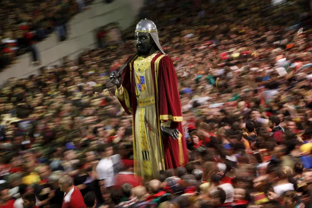 A figure of a giant stands as revellers take part in the Patum in the Catalan village of Berga, Spain Friday, May 27, 2016. The Patum of Berga is a popular festival whose origin can be traced to medieval festivities that is celebrated each year in the Catalan city of Berga during Corpus Christi. It consists of a series of dances by townspeople dressed as mystical and symbolical figures accompanied by the rhythm of a drum. One of the protagonist of La Patum is the fire, and the climax of the festival is the Salt de Plens (Fire Demons), who set the square on fire with hundreds of firecrackers burning at the same time. (Photo by Emilio Morenatti/AP Photo)