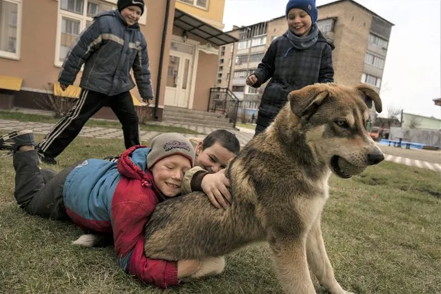 Children play with a dog in Bucha, on the outskirts of Kyiv, Ukraine, Friday, April 8, 2022. (Photo by Rodrigo Abd/AP Photo)