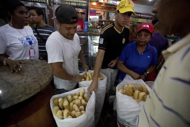 In this March 17, 2017 photo, employees of the Minka state-run bakery carry bags of cheap bread to be distributed to state-run grocery stores in Caracas, Venezuela. The government said it was taking over the Mansion’s Bakery for 90 days, turning control over to a pro-government neighborhood committee given the task of distributing bags of staples door-to-door. (Photo by Fernando Llano/AP Photo)