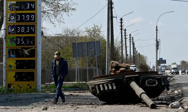Ukrainian serviceman walks past the turret of a Russian tank next to a destroyed petrol station in the village of Skybyn, northeast of Kyiv on May 2, 2022. The snaking queues of cars that returned to many Ukrainian roads last week showcase the success of Russia's seeming effort to inflict as much pain on its western neighbour as possible. (Photo by Sergei Supinsky/AFP Photo)