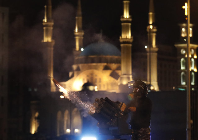 A riot police officer fires tear gas from a launcher against anti-government protesters trying to enter parliament square in downtown Beirut, Lebanon, Saturday, December 14, 2019. The recent clashes marked some of the worst in the capital since demonstrations began two months ago. The rise in tensions comes as politicians have failed to agree on forming a new government. (Photo by Hussein Malla/AP Photo)