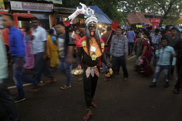 An Indian man stands dressed like Hindu goddess Kali to attract alms from devotees during the Ambubasi festival at the Kamakhya Hindu temple in Gauhati, India, Sunday, June 22, 2014. The annual festival where hundreds of holy men from an esoteric form of Hinduism, gather to perform rituals at the temple begins on June 22. (Photo by Anupam Nath/AP Photo)