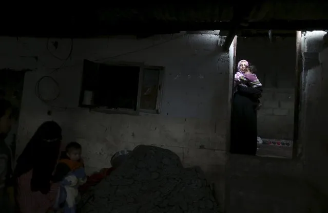 A Palestinian woman carries her daughter at her house during a power cut in the northern Gaza Strip March 25, 2015. (Photo by Mohammed Salem/Reuters)