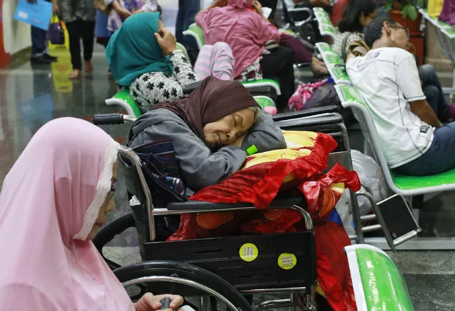 A patient takes a nap on her wheelchair as she waits with others at the registration desk at Dharmais Cancer Hospital in Jakarta, Indonesia, Monday, May 15, 2017 as the hospital's information system is in trouble by cyberattack. Global cyber chaos was spreading Monday as companies booted up computers at work following the weekend's worldwide “ransomware” cyberattack. The extortion scheme created chaos in 150 countries and could wreak even greater havoc as more malicious variations appear. (Photo by Dita Alangkara/AP Photo)