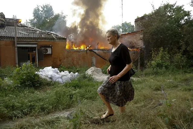 A woman runs from a house that's on fire after shelling in Donetsk, on the territory which is under the Government of the Donetsk People's Republic control, eastern Ukraine, Friday, June 3, 2022. (Photo by Alexei Alexandrov/AP Photo)