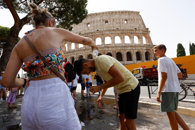 A woman pours water on a man near the Colosseum, during a heatwave across Italy, as temperatures are expected to rise further in the coming days, in Rome, Italy on July 18, 2023. (Photo by Remo Casilli/Reuters)