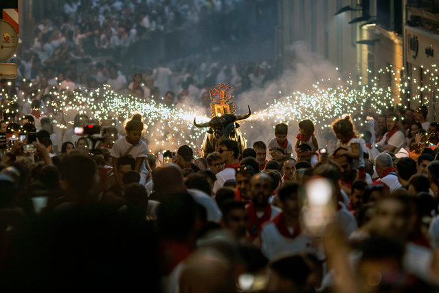 People attend the traditional “Bull of Fire” parade during the San Fermin festival in Pamplona, northern Spain on July 8, 2023. Pamplona's Running of the Bulls, known locally as Sanfermines, is held annually from 06 to 14 July in commemoration of the city's patron saint. Visitors from all over the world attend the fiesta. (Photo by Rodrigo Jimenez/EPA/EFE)