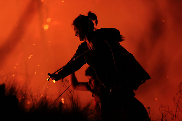 People attempt to extinguish a forest fire in Intiyaco, Cordoba province, Argentina, on September 22, 2024. The forest fires that have been raging for weeks in the Argentine province of Córdoba (central Argentina) intensified on September 20 with two intense outbreaks that forced the preventive evacuation of residents in rural areas, provincial authorities reported. (Photo by AFP Photo/Stringer)