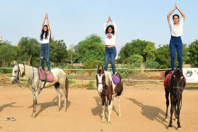 Students perform yoga on horseback during an event ahead of International Yoga Day, in Ahmedabad on June 19, 2022. (Photo by Sam Panthaky/AFP Photo)