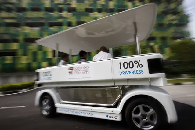 People ride on a driverless electric vehicle at the Nanyang Technological University (NTU) in Singapore, 2013. (Photo by Edgar Su/Reuters)