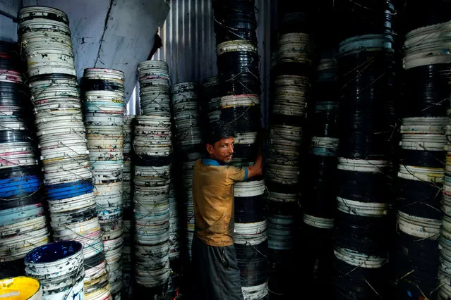 A worker carries paint containers inside a recycling workshop in Mumbai, India August 18, 2017. (Photo by Danish Siddiqui/Reuters)