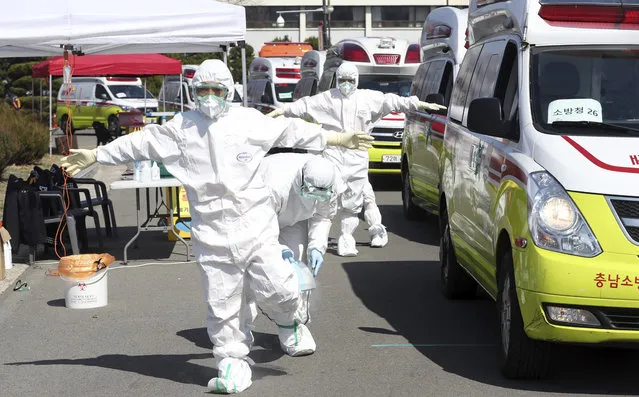 Members of paramedics wearing protective gears are disinfected near their ambulances in Daegu, South Korea, Friday, March 6, 2020. Seoul expressed “extreme regret” Friday over Japan's ordering 14-day quarantines on all visitors from South Korea due to a surge in viral infections and warned of retaliation if Tokyo doesn't withdraw the restrictions. (Photo by Kim Hyun-tai/Yonhap via AP Photo)