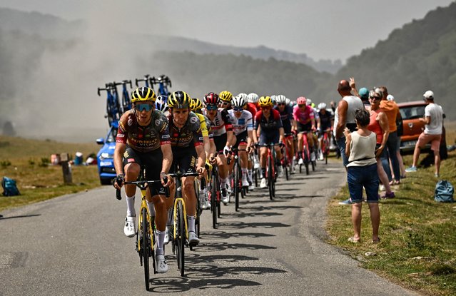 Smoke billows along the roadside as Jumbo-Visma team's French rider Christophe Laporte leads the pack of riders as they cycle during the 17th stage of the 109th edition of the Tour de France cycling race, 129,7 km between Saint-Gaudens and Peyragudes in southwestern France, on July 20, 2022. (Photo by Marco Bertorello/AFP Photo)
