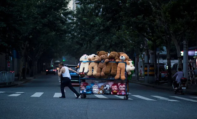 This picture taken on July 12, 2016 shows a street vendor pulling his cart packed with stuffed animals along a street in Shanghai. (Photo by Johannes Eisele/AFP Photo)