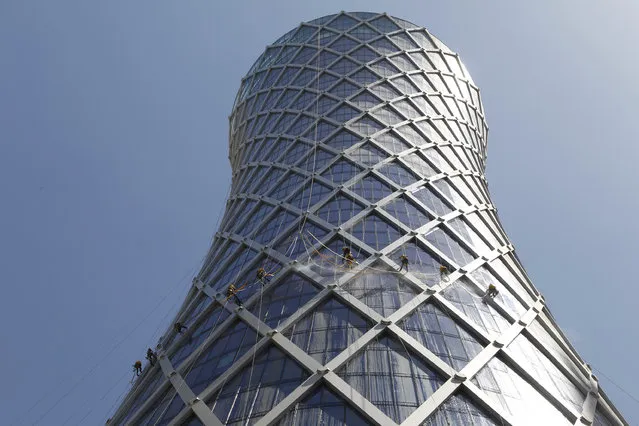 Workers suspended on ropes clean the glass windows at the Tornado tower in Doha March 20, 2011. (Photo by Fadi Al-Assaad/Reuters)