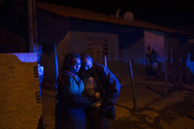 In this July 13, 2016 photo, an eyewitness stands with a woman outside a bar where a pre-candidate for local council was shot dead in Mage, in greater Rio de Janeiro, Brazil. According to local news reports the 49-year-old woman was shot by four gunmen while in a bar with a friend and her partner. The woman is the 11th politician murdered in the greater Rio area since November, and police have not been able to determine the motives for the killings. (Photo by Felipe Dana/AP Photo)