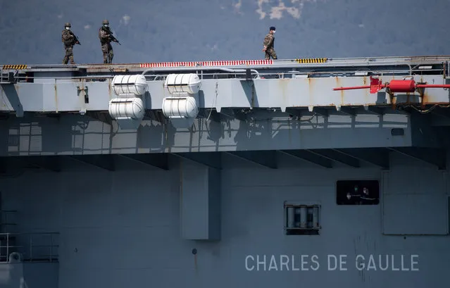 French navy soldiers wearing face masks stand onboard the French aircraft carrier Charles de Gaulle on April 12, 2020, as it arrives in the southern French port of Toulon with sailors onboard infected with COVID-19 (novel coronavirus). Fifty sailors aboard the Charles de Gaulle aircraft carrier, the flagship of the French navy, have contracted the novel coronavirus the armed forces ministry said on April 11. The nuclear-powered ship arrived in Toulon on April 12 so that those infected can begin a period of quarantine on dry land, according to the ministry. (Photo by Christophe Simon/AFP Photo)
