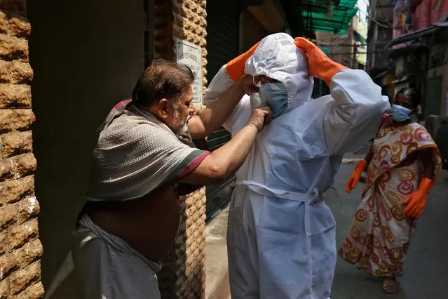 A resident adjusts the face mask of a health worker during a sanitization drive to control the spreading of coronavirus disease (COVID-19), in a neighbourhood in Kolkata, April 16, 2020. (Photo by Rupak De Chowdhuri/Reuters)
