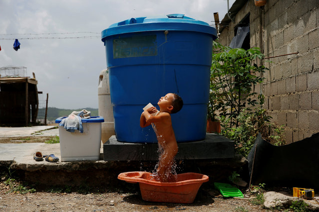 Luis Espinoza, 3, takes a bath next to a water tank, at his home in Charallave, Venezuela July 7, 2016. Luis's mother Oleydy Canizalez plans to have a sterilization surgery. (Photo by Carlos Garcia Rawlins/Reuters)