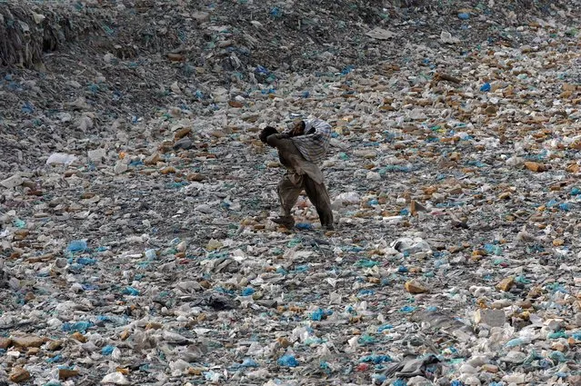 A boy walks with a sack of recyclables collected from a drainage channel, littered with heaps of polythene bags, ahead of the World Environment Day, in Karachi, Pakistan on June 4, 2020. (Photo by Akhtar Soomro/Reuters)