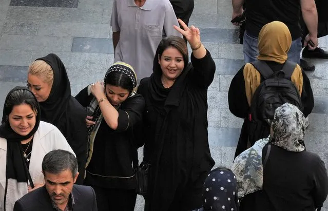 A woman flashes a victory sign as she walks around in the old main bazaar of Tehran, Iran, Saturday, October 1, 2022. Thousands of Iranians have taken to the streets over the last two weeks to protest the death of Mahsa Amini, a 22-year-old woman who had been detained by the morality police in the capital of Tehran for allegedly wearing her mandatory Islamic veil too loosely. (Photo by Vahid Salemi/AP Photo)