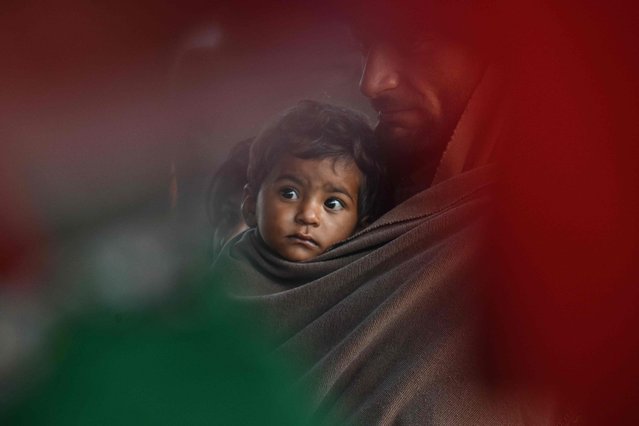 A devotee holding his child takes part in a journey towards the shrine of the Sufi saint Hazrat Daud Bandagi Kirmani, ahead of the annual five-day festival, in Sharaqpur in Pakistan's Punjab province on March 9, 2025. (Photo by Arif Ali/AFP Photo)