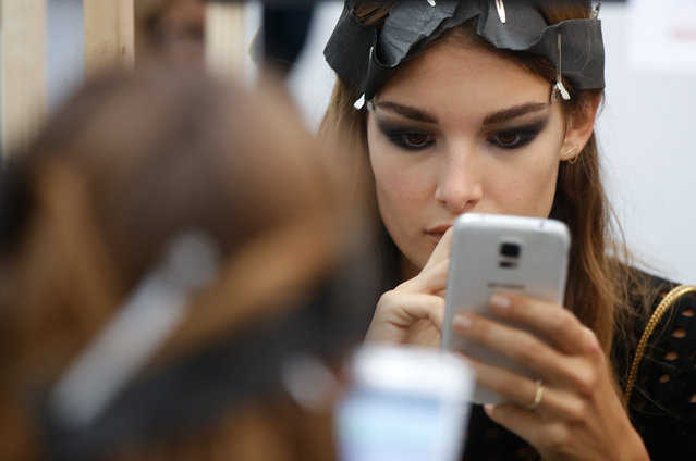 A model checks her cellular phone in the backstage prior to the Costume National women's spring-summer 2016 fashion show, part of the Milan Fashion Week, unveiled in Milan, Italy, Thursday, September 24, 2015. (Photo by Luca Bruno/AP Photo)