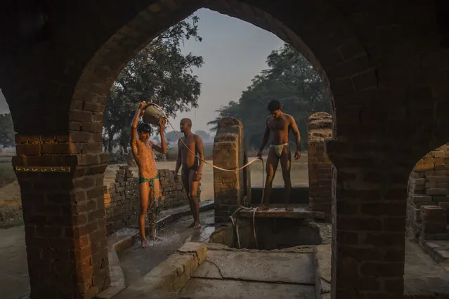 In this November 22, 2017 photo, an Indian Kushti wrestler bathes near a well as others wait their turn after their daily training at an akhada, a kind of wrestling hostel at Bahadurgarh, in Haryana, India. (Photo by Dar Yasin/AP Photo)