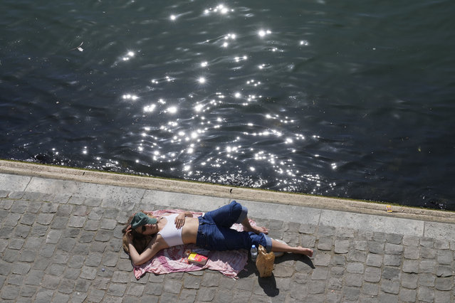 A woman enjoys the sun along the Seine river during lunch time in Paris, Friday, April 4, 2025. (Photo by Michel Euler/AP Photo)