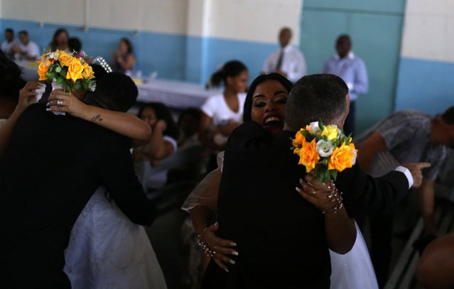 Inmates embrace their brides during a community wedding organized by Coracao Solidario (Solidarity Heart) at the male prison Lemos de Brito at Bangu, largest prison complex in Rio de Janeiro, Brazil on December 18, 2017. (Photo by Pilar Olivares/Reuters)
