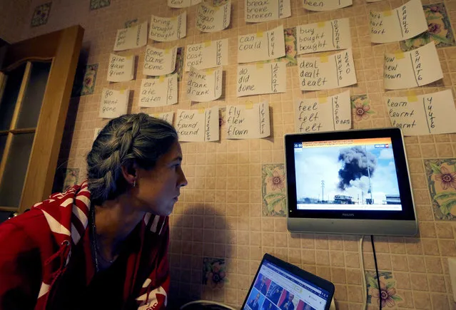A woman watches a Russia-24 news program on TV allegedly showing Russian airstrikes in Syria, in a room with English verbs on a wall in St. Petersburg, Russia, 30 September 2015. Russia on 30 September said it had begun airstrikes against the Islamic State terrorist organization in war-torn Syria, but the Syrian opposition claimed that the raids had hit rebel-held territory and killed civilians. (Photo by Anatoly Maltsev/EPA)