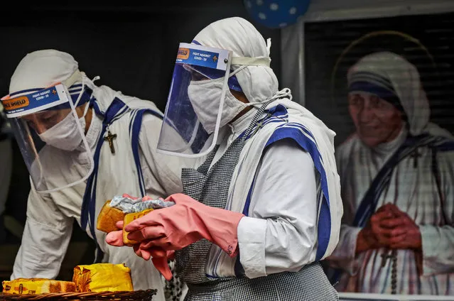 Nuns of the Missionaries of Charity, the order founded by Saint Teresa, wearing masks and face shields as precaution against the coronavirus distribute food to poor and homeless people in Kolkata, India, Wednesday, August 26, 2020. Wednesday marked the birth anniversary of Nobel laureate Mother Teresa, a Catholic nun who spent 45-years serving the poor, the sick, the orphaned, and the dying. (Photo by Bikas Das/AP Photo)