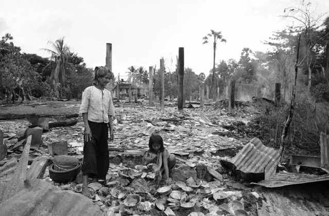 Cambodian woman and a little girl try to salvage belongings from what was once their home in Taing Kauk, about 47 miles North of Phnom Penh on October 9, 1970. Enemy forces occupied the village, then repulsed a Cambodian counter attack. The Cambodian forces used air and artillery strikes to drive the enemy out, resulting in flattening almost the entire village. The villagers had fled when the enemy arrived. (Photo by Ghislain Bellorget/AP Photo)