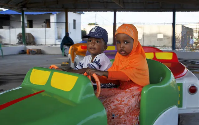 In this photo taken Sunday, August 21, 2016, Somali children play on a ride at the Peace Garden public park in Mogadishu, Somalia. War-weary Somalis are trying to relax and rebuild their country after decades of violence, but the homegrown Islamic extremists al-Shabab keep striking at the heart of its seaside capital, killing scores of people so far this year. (Photo by Farah Abdi Warsameh/AP Photo)