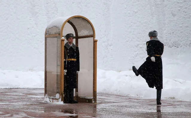 A honor guard soldier stands in guard at the Tomb of Unknown Soldier as another soldier march along the snow-covered Kremlin wall in Moscow, Russia, 31 January 2018. Long lasting snowfalls have been predicted in Moscow. (Photo by Maxim Shipenkov/EPA/EFE)