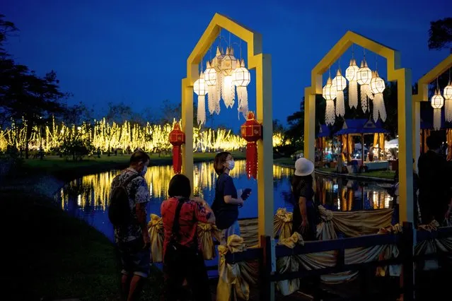 People cross a bridge illuminated with lanterns in Suan Luang Rama IX park in Bangkok on December 2, 2022. (Photo by Jack Taylor/AFP Photo)