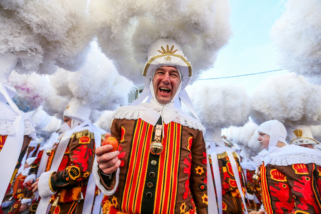 Festival participant known as “Gilles”, wearing traditional costume and hat made of ostrich feathers, throws oranges during Carnival celebrations in the streets of Binche, Belgium, 13 February 2018. The Carnival de Binche is a popular historical cultural event that was named a Masterpiece of the Oral and Intangible Heritage of Humanity by UNESCO in 2003. (Photo by Stephanie Lecocq/EPA/EFE)