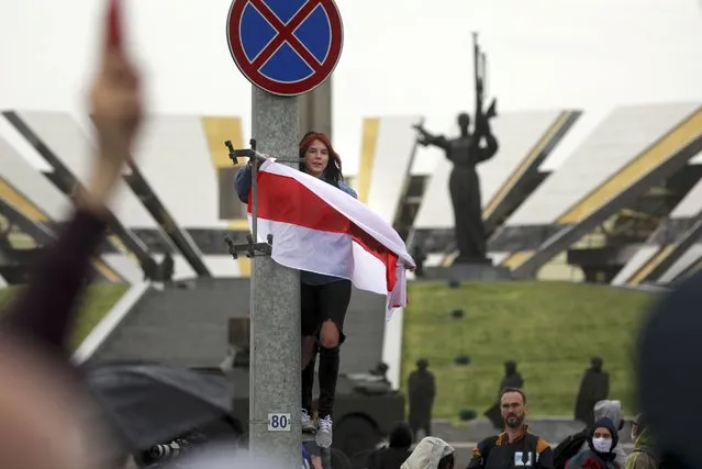 A woman holds an old Belarusian national flag at the WWII monument during an opposition rally to protest the official presidential election results in Minsk, Belarus, Sunday, September 27, 2020. (Photo by TUT.by via AP Photo)